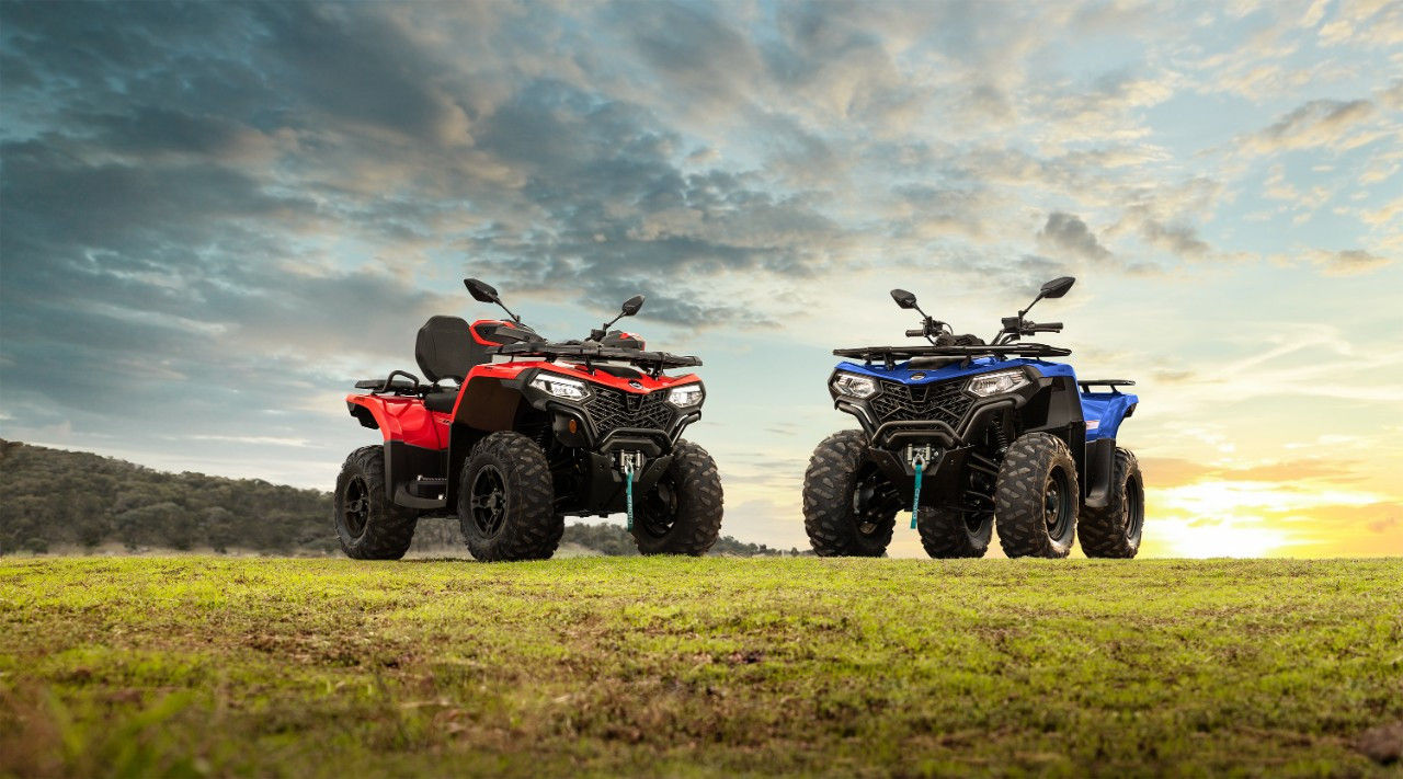 два квадроцикли CFMOTO CFORCE 520 L червоний і блакитний стоять на лузі