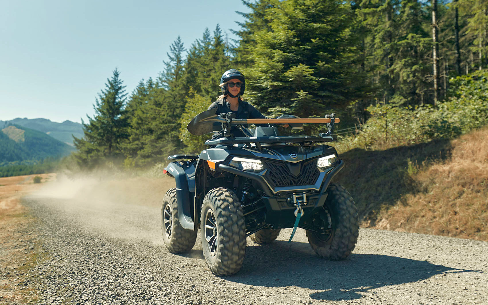Жінка їде на квадроциклі CFMOTO CFORCE 625 лісовою дорогою